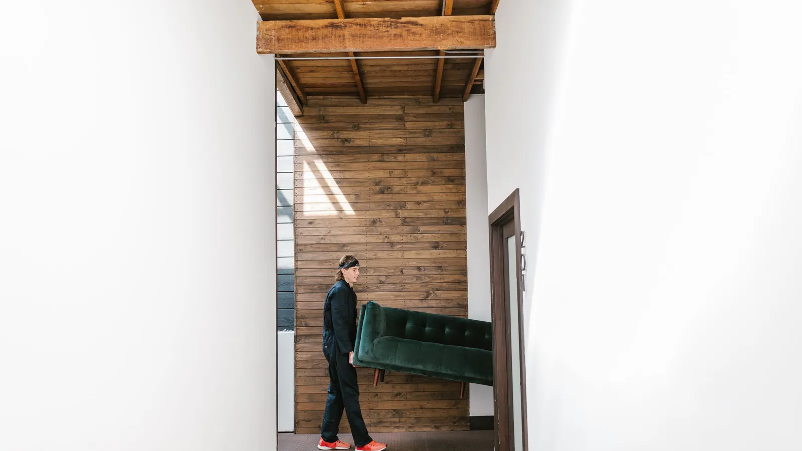 Person carrying a sofa through a tall interior doorway