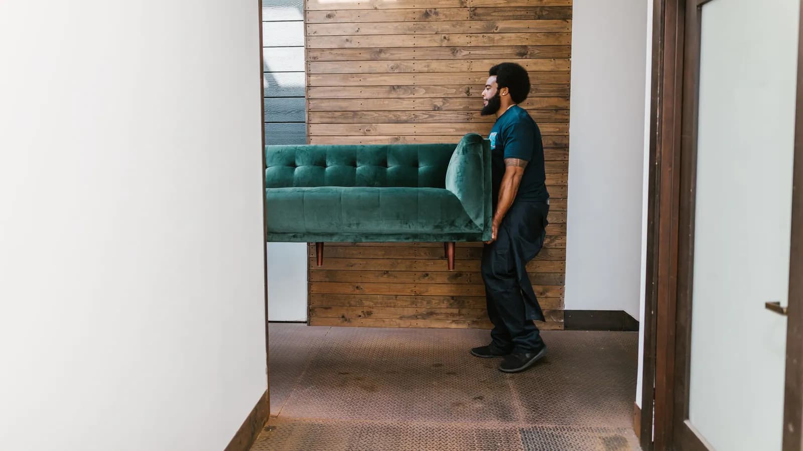 Person carrying a sofa through a residential doorway