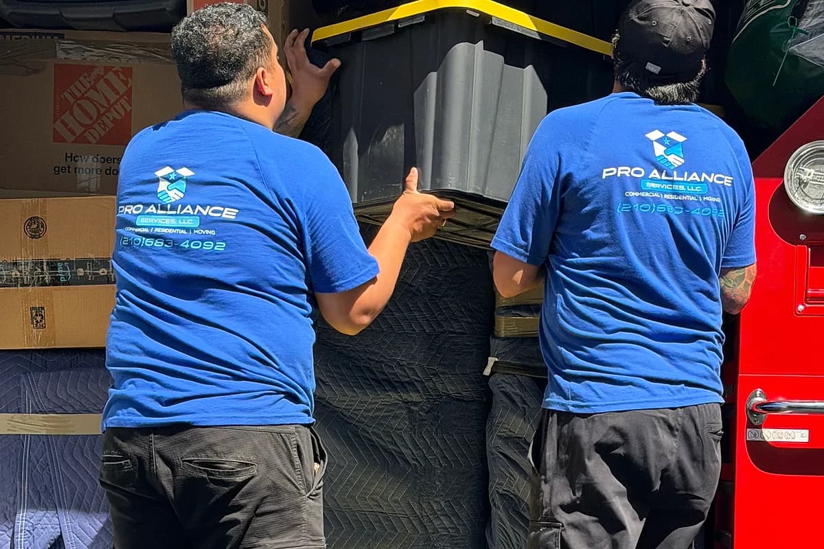Two Pro Alliance movers loading packed totes and cartons into a moving truck