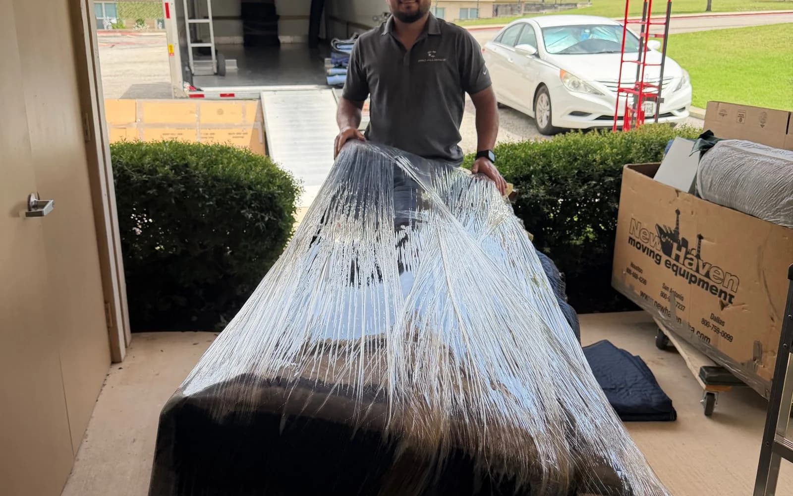 Pro Alliance movers secure a loaded truck with straps before a highway drive