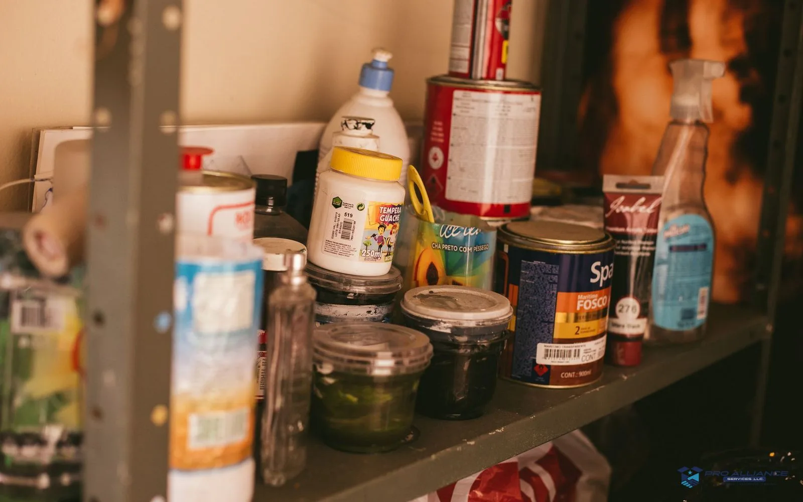 Garage shelving stocked with paint cans, spray cans, and fuel containers