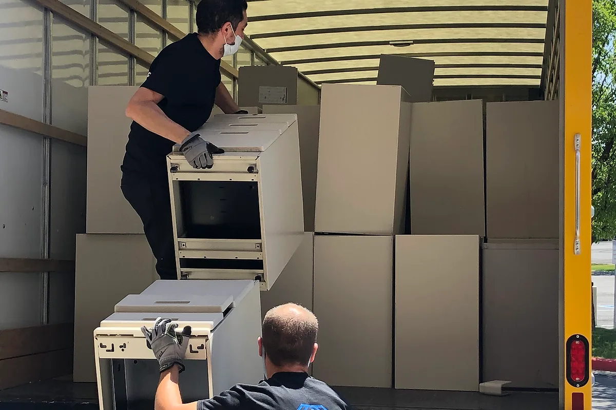 Pro Alliance crew loading office cabinets and workstation components into a moving truck