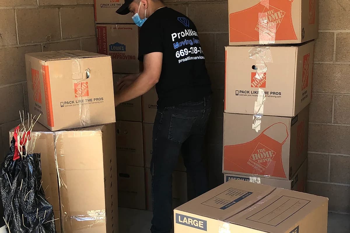 Pro Alliance mover stacking packed cartons in a storage unit during a relocation