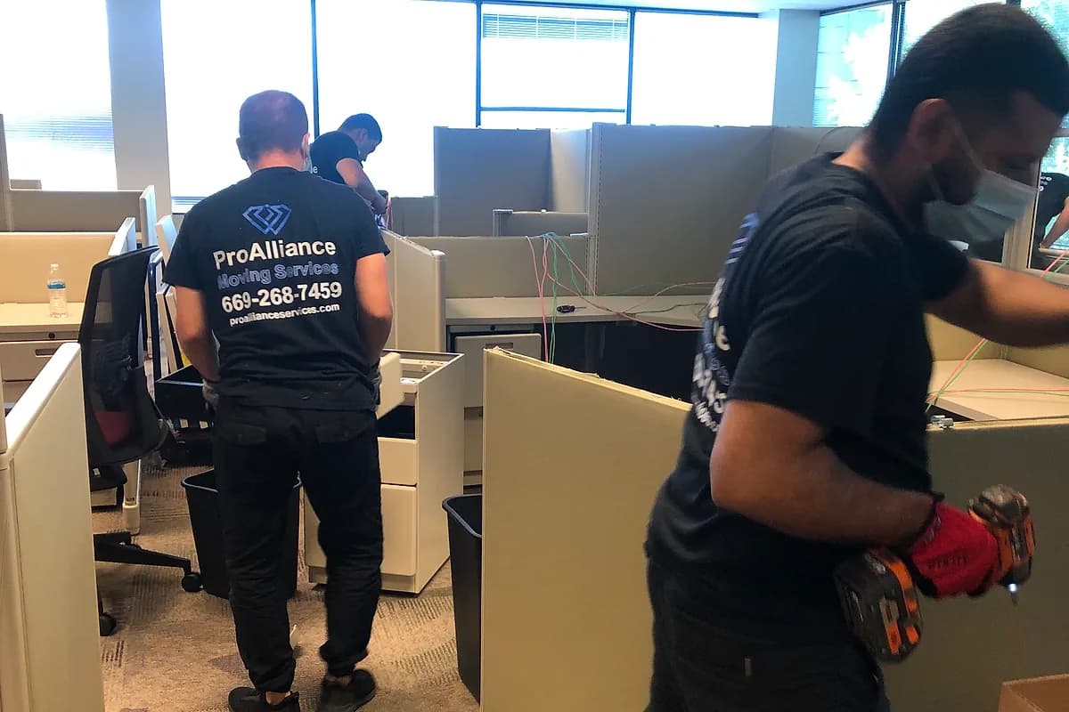 Pro Alliance crew disassembling office workstations with power tools to keep a move on schedule