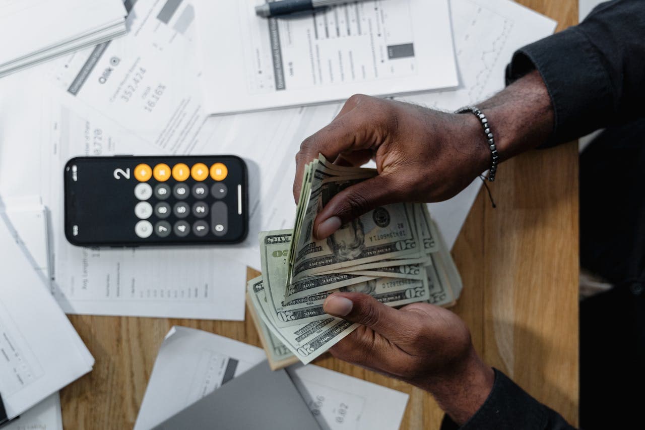 A person counting dollar bills and using calculator to calculate the cost of living in Castle Hills