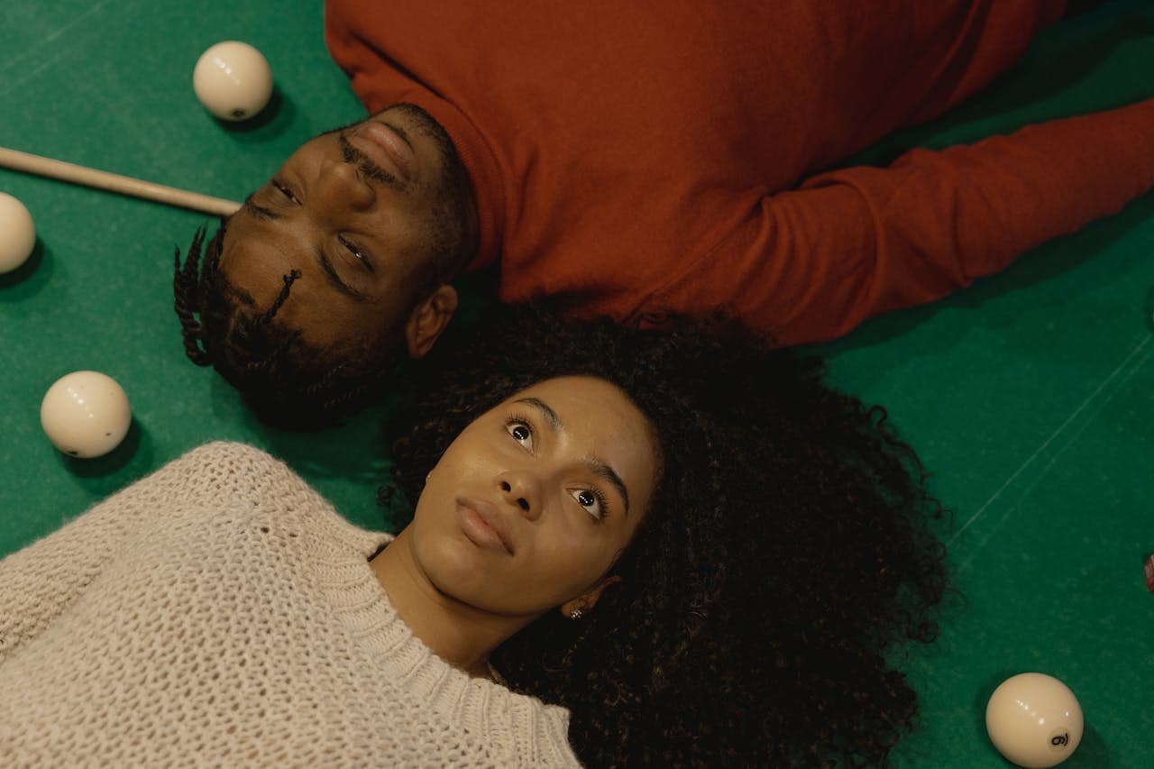 A couple lying on the pool table thinking about storage tips for pool tables during a temporary move