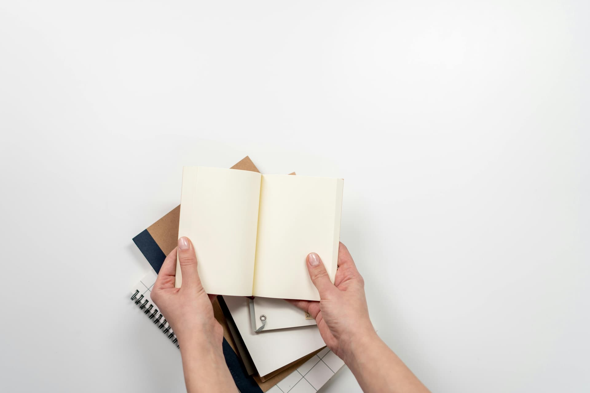 A notebook on top of some books on a white table.