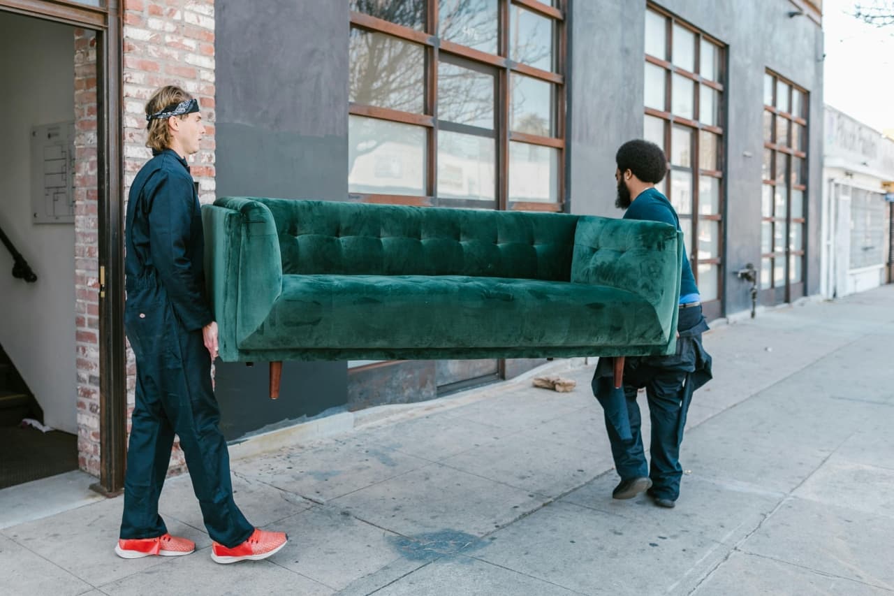 two men holding the couch