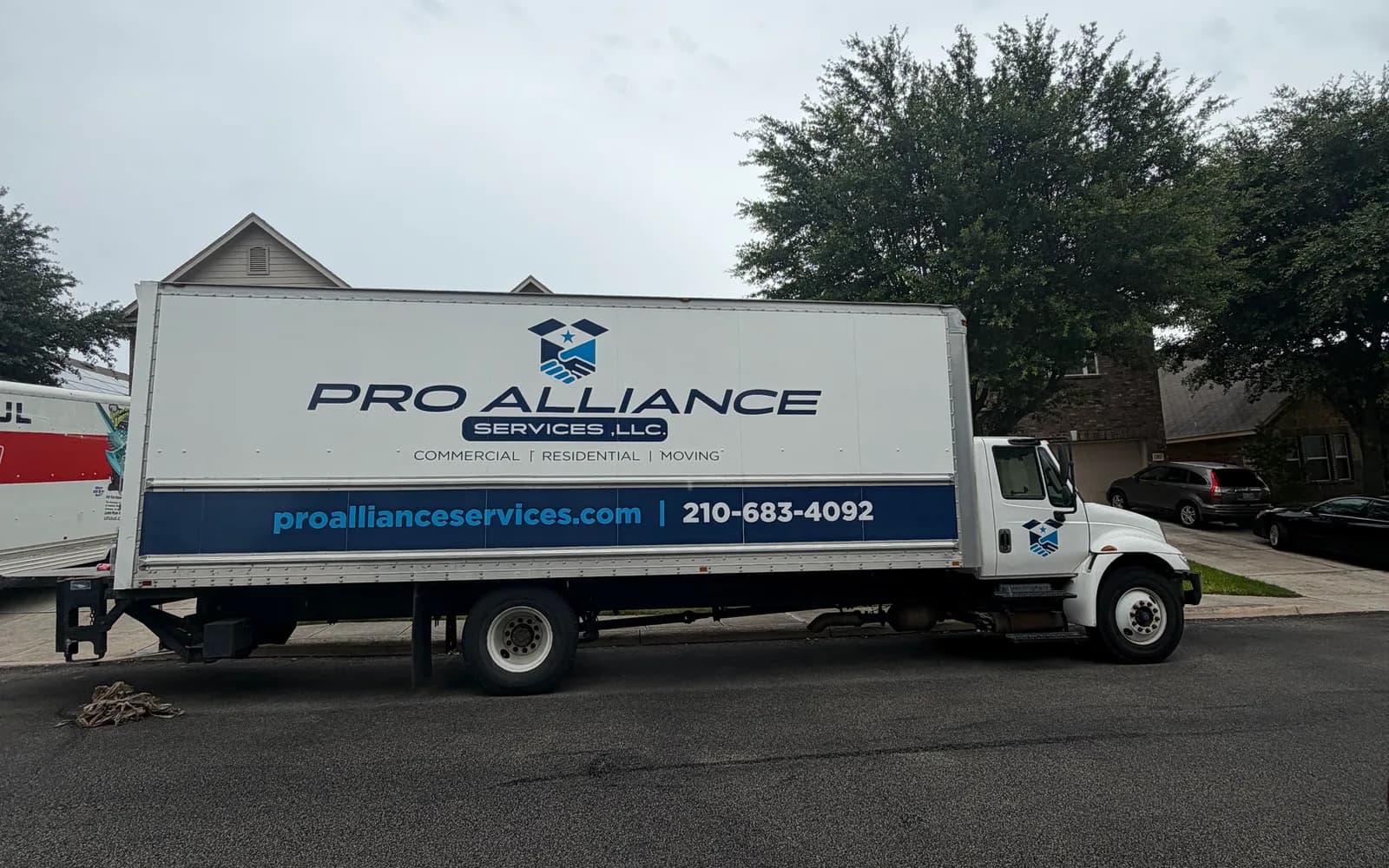 Pro Alliance branded box truck parked on a residential street under an overcast sky