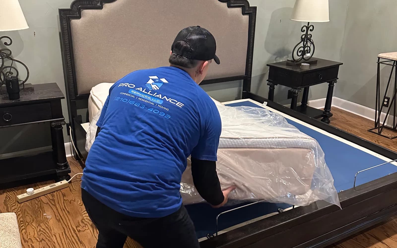 A Pro Alliance crew member disassembling a bed frame in an emptied bedroom