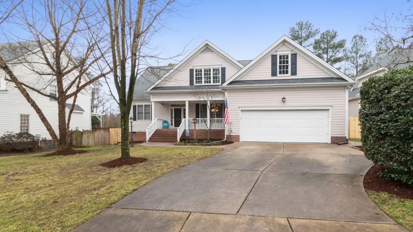 A driveway approach to a large home with trees