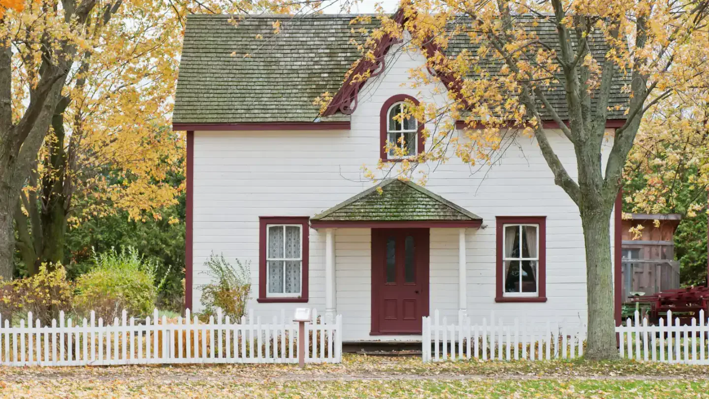 An older single-story home with mature trees and a narrow front walk