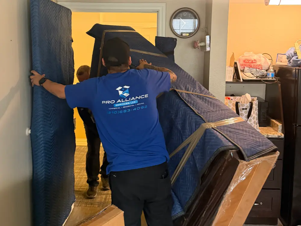 Crew carrying blanket-wrapped furniture through a hallway