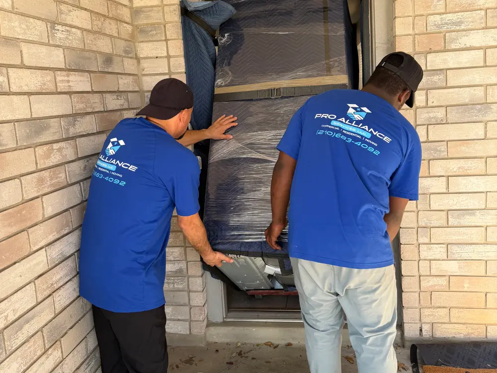 Crew guiding a wrapped piece through the front door of a home