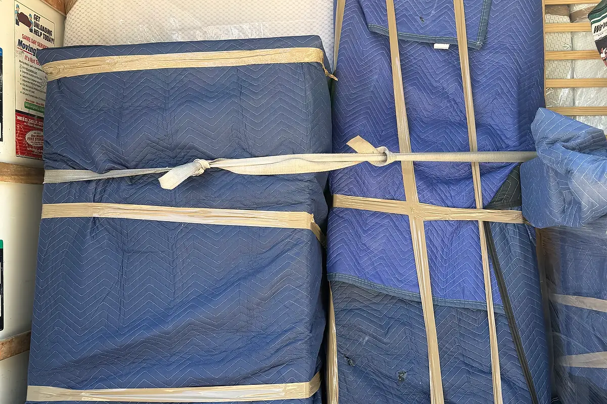 Blanket-wrapped and strapped furniture stacked tightly inside a Pro Alliance moving truck