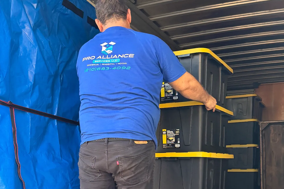 Pro Alliance mover rolling a stack of packed totes on a dolly into a moving truck