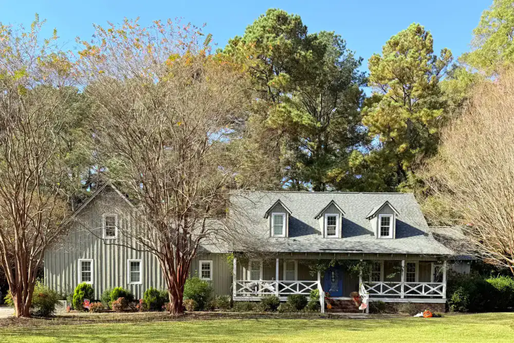 Two-story home with trees along the front approach