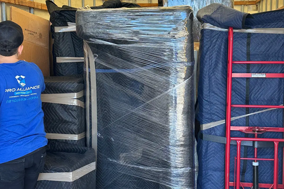 Interior of a loaded Pro Alliance truck with blanket-wrapped furniture and a hand truck stowed alongside