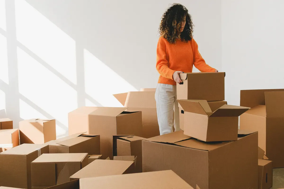 Person folding a cardboard box among moving supplies