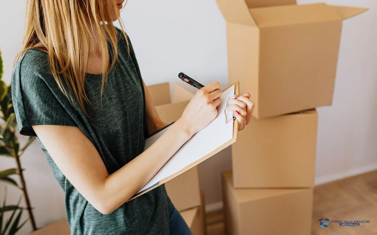 A person reviews a checklist on a clipboard beside stacked moving boxes