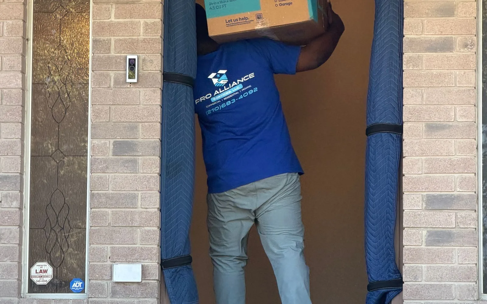 A Pro Alliance crew member carries a box past a padded door jamb