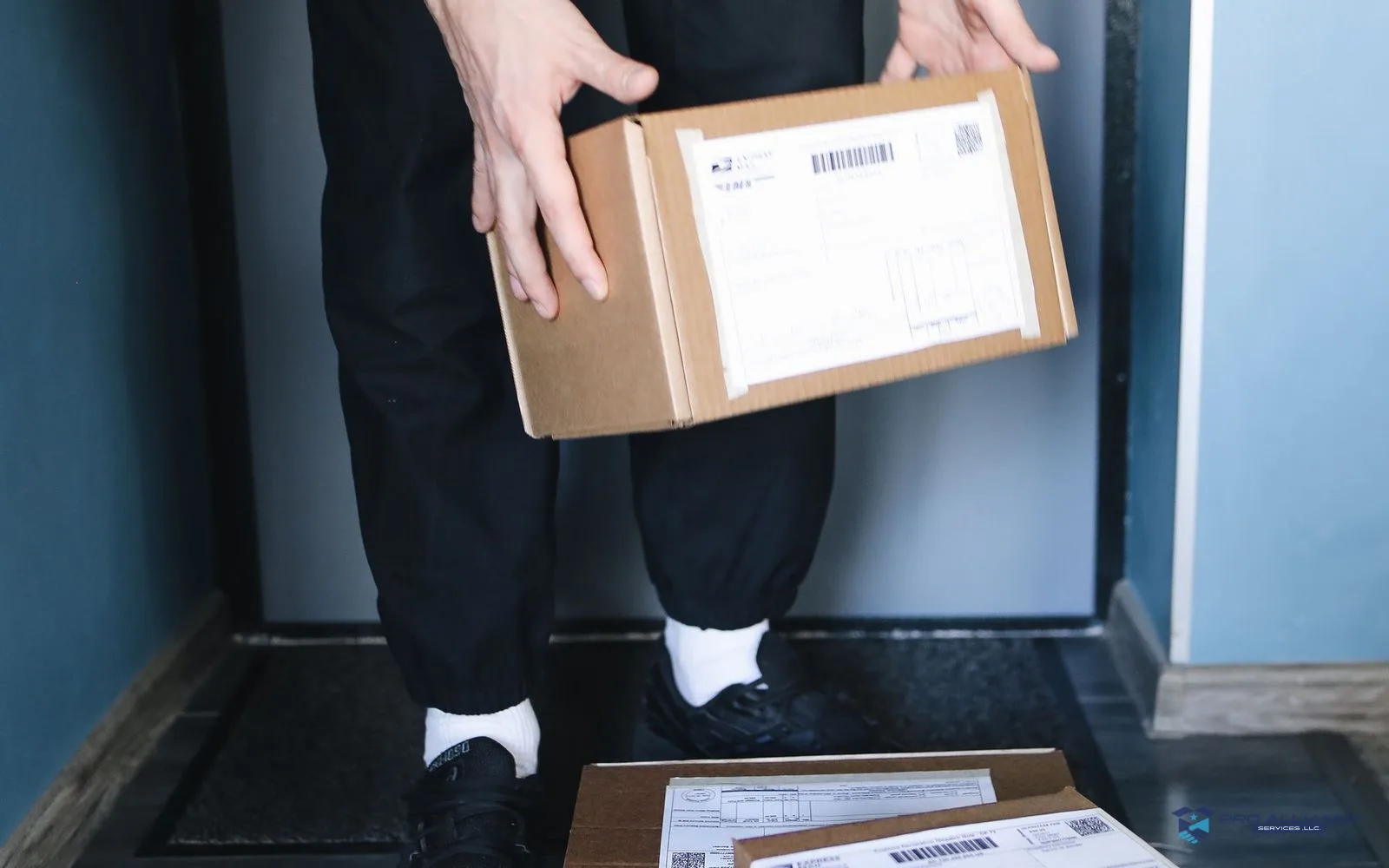 A person carrying a moving carton through a doorway