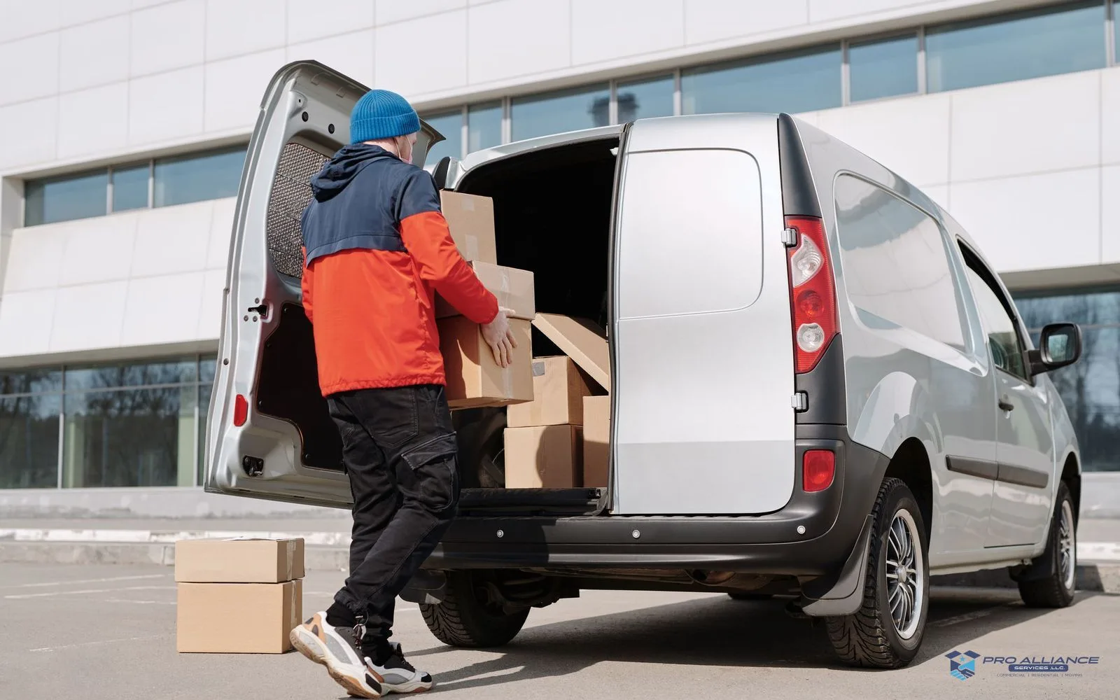 A person loading cardboard boxes into the open rear of a cargo van