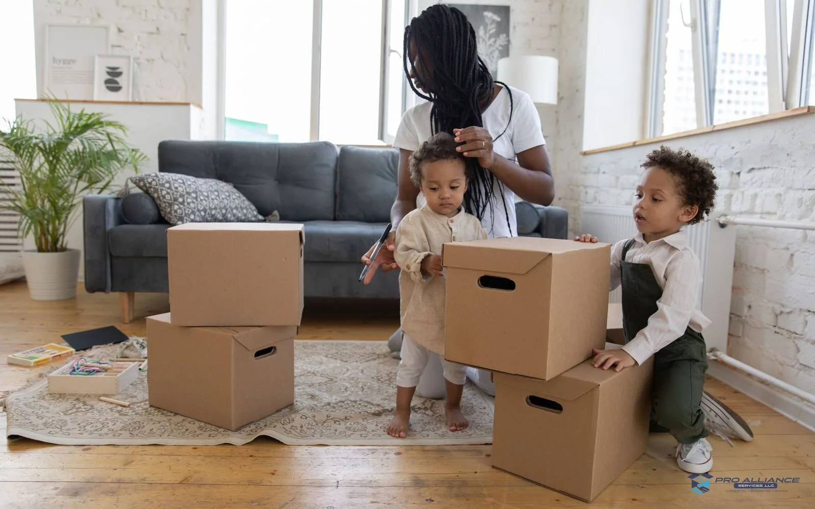 An adult and two children packing cardboard boxes in a living room