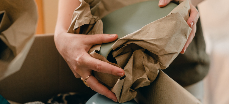 person wrapping up a plate before putting it in a box