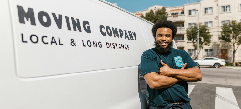 Confident professional mover stands beside a 'Moving Company' van, ready to move a pool table safely to a new location.