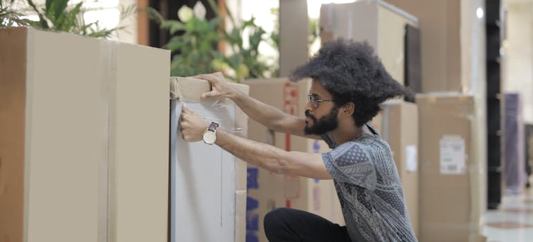 A person unpacking in the office after reading the packing supplies checklist for an office relocation.
