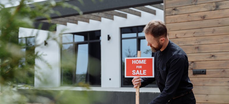 A man next to the home for sale sign