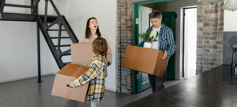 A family carrying boxes into their new home, showing what moving day looks like when living in Fair Oaks Ranch.