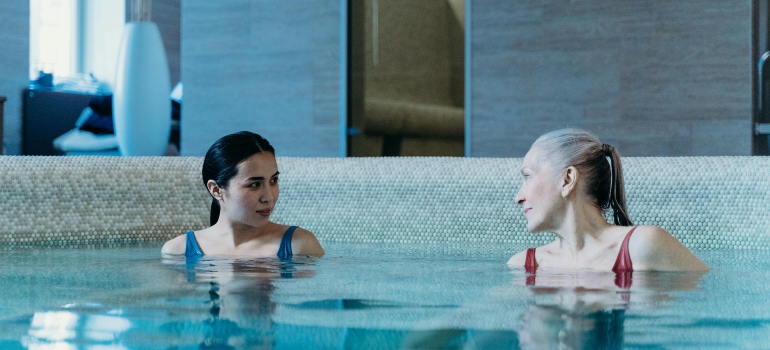 Two women enjoying a swim in the pool, reflecting the lively cities in Bexar County for an active lifestyle.