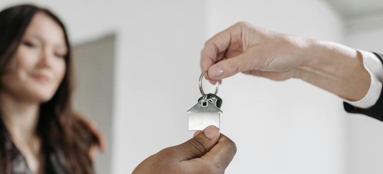 Close-up of a hand giving house keys to a new owner inside a home.
