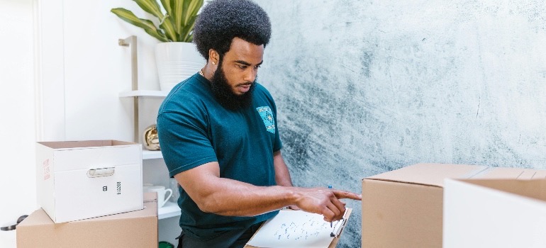 man in a green shirt, labeling boxes and making moving lists