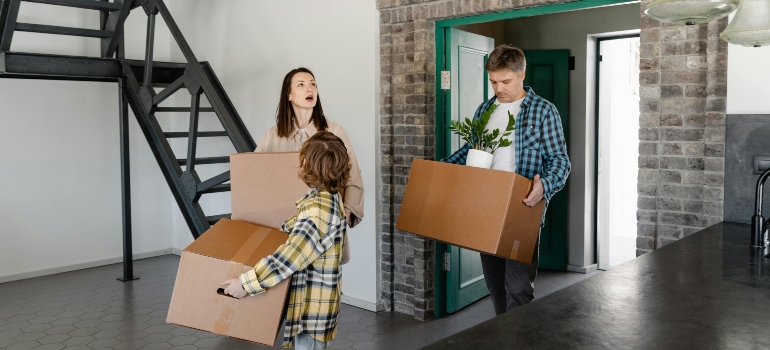 A New Homeowners Looking at the House while Carrying a Box