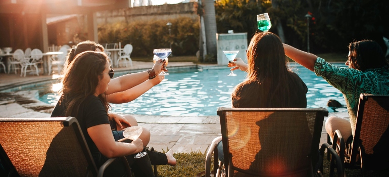 Friends enjoying drinks by a pool after settling into a new home.