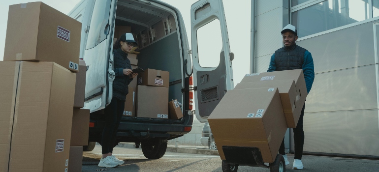 Professional movers handling packed office boxes outside a commercial building.