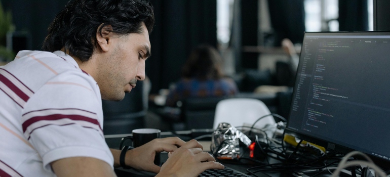 Close-up of technician working on computer code and securing systems before a company move.