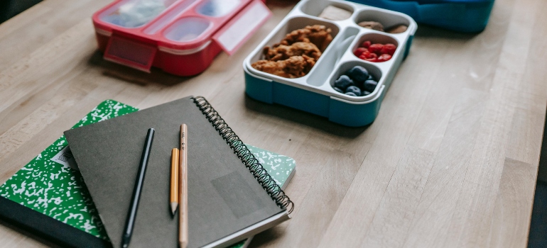 Lunch boxes behind notebooks on table