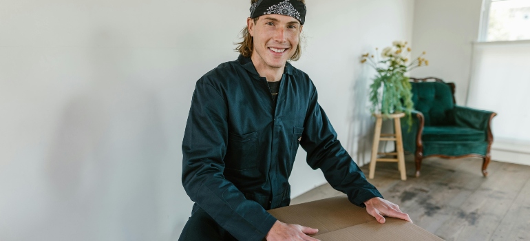 Mover closing a sturdy cardboard box, showing how to pack fragile things safely when moving.