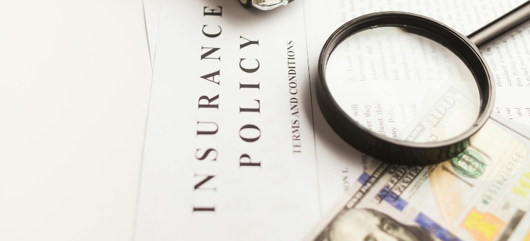 Close-up of insurance policy documents and money related to moving a grand piano long distance coverage.