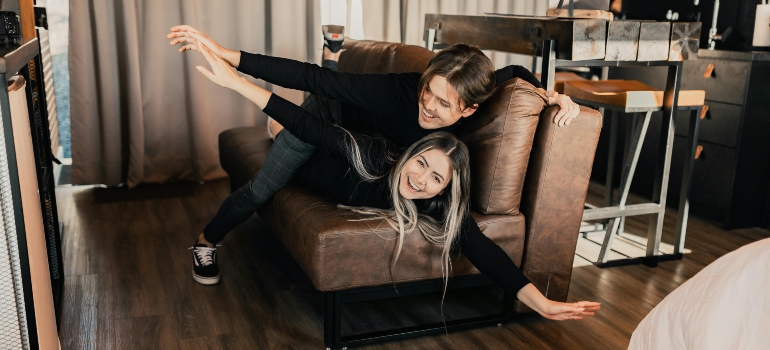 Two people adjusting a sofa inside a room to check fit and placement after moving in.
