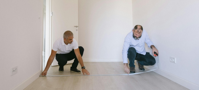 Homeowners measuring a room before placing furniture, following practical moving tips for seniors during downsizing.