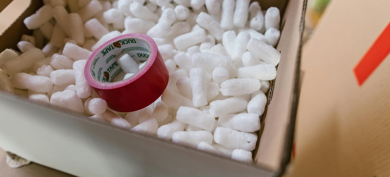 Close view of packing box with tape and protective packing peanuts used to protect household belongings.