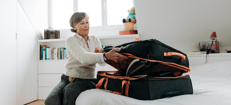 Senior woman packing a suitcase with daily items, applying moving tips for seniors before relocating.
