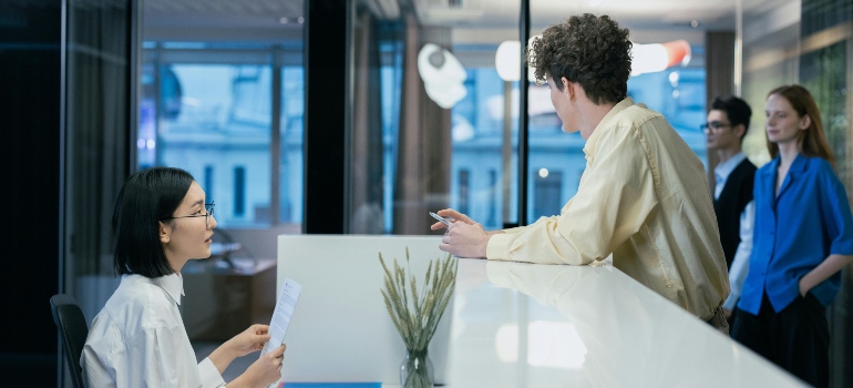 Employees discussing office relocation details at reception desk.