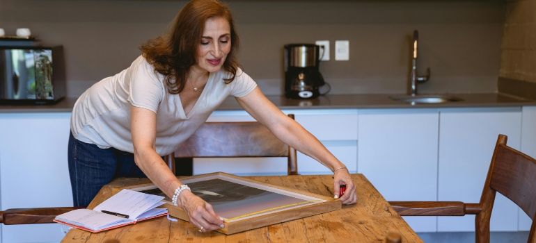 Person aligning frame on table to pack wall art when moving safely