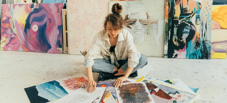 Artist arranging paintings on floor before packing artwork for relocation